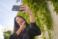 Young happy and beautiful Asian Korean woman enjoying outdoors taking selfie with mobile phone at village garden playful and Royalty Free Stock Photo