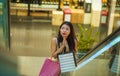 Young happy and beautiful Asian Korean woman at mall escalator carrying shopping bags in mall buying cheerful around fashion stor Royalty Free Stock Photo