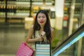 Young happy and beautiful Asian Korean woman at mall escalator carrying shopping bags in mall buying cheerful around fashion stor Royalty Free Stock Photo