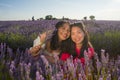 Young happy and beautiful Asian korean woman playing on lavender flowers field with her hispanic girlfriend enjoying sweet