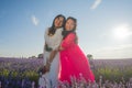 Young happy and beautiful Asian korean woman playing on lavender flowers field with her hispanic girlfriend enjoying sweet