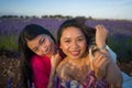 Young happy and beautiful Asian korean woman playing on lavender flowers field with her hispanic girlfriend enjoying sweet