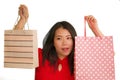 Young happy and beautiful Asian Korean woman in red dress smiling cheerful holding shopping bags as excited shopaholic girl Royalty Free Stock Photo