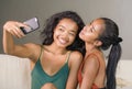 Young happy and beautiful Asian sisters or girlfriends couple smiling cheerful taking selfie photo with mobile phone at home