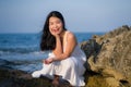 Young happy and beautiful Asian woman by the sea - Attractive Korean girl in white dress enjoying relaxed summer holidays at Royalty Free Stock Photo