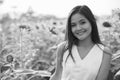 Young happy beautiful Asian woman smiling in the field of blooming sunflowers Royalty Free Stock Photo