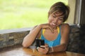 Young happy beautiful and attractive Asian woman sitting in coffee shop using internet app on mobile phone laughing excited outdoo Royalty Free Stock Photo