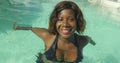 Happy and beautiful black African American woman in bikini having fun at tropical beach resort swimming pool relaxed and playful Royalty Free Stock Photo