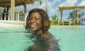 Happy and beautiful black African American woman in bikini having fun at tropical beach resort swimming pool relaxed and playful Royalty Free Stock Photo