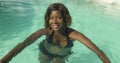 Happy and beautiful black African American woman in bikini having fun at tropical beach resort swimming pool relaxed and playful Royalty Free Stock Photo