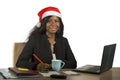 Young happy and beautiful black afro American business woman in Santa Christmas hat working at office computer desk smiling succes Royalty Free Stock Photo