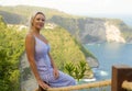 Young happy and beautiful blond woman relaxed at tropical beach cliff viewpoint enjoying Summer holidays getaway carefree at Royalty Free Stock Photo