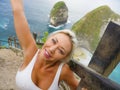 Young happy and beautiful blond woman smiling cheerful at tropical beach cliff landscape enjoying Summer holidays getaway carefree Royalty Free Stock Photo