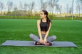 Young happy and beautiful brunette girl doing yoga workout in park, sitting in lotus pose meditating enjoying retreat in balance a Royalty Free Stock Photo