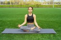 Young happy and beautiful brunette girl doing yoga workout in park, sitting in lotus pose meditating enjoying retreat in balance a Royalty Free Stock Photo