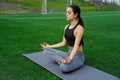 Young happy and beautiful brunette girl doing yoga workout in park, sitting in lotus pose meditating enjoying retreat in balance a Royalty Free Stock Photo