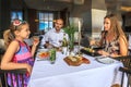 Young happy beautiful Caucasian family of father, mother and daughter have dinner by served restaurant table together