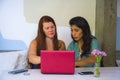 Young happy and beautiful caucasian and hispanic women working at office cafe with laptop computer as digital business partners Royalty Free Stock Photo