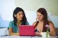 Young happy and beautiful caucasian and hispanic women working at office cafe with laptop computer as digital business partners Royalty Free Stock Photo