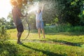 Young happy beautiful couple hosing in the garden, summer happiness and love concept, poured water from a garden hose of a spray Royalty Free Stock Photo