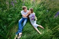 Young happy beautiful couple sitting in green meadow Royalty Free Stock Photo