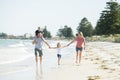 Young happy and beautiful family mother father holding hand of son and daughter walking joyful on the beach enjoying Summer holida Royalty Free Stock Photo