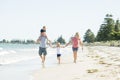 Young happy and beautiful family mother father holding hand of son and daughter walking joyful on the beach enjoying Summer holida Royalty Free Stock Photo