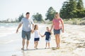 Young happy and beautiful family mother father holding hand of son and daughter walking joyful on the beach enjoying Summer holida Royalty Free Stock Photo