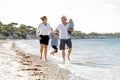 Young happy beautiful family walking together on the beach enjoying summer holidays Royalty Free Stock Photo