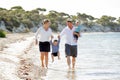Young happy beautiful family walking together on the beach enjoying summer holidays Royalty Free Stock Photo