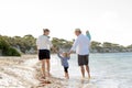 Young happy beautiful family walking together on the beach enjoying summer holidays Royalty Free Stock Photo