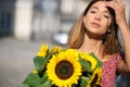 Young happy beautiful girl is walking in dress with a bouquet of sunflowers on a city street. Autumn concept Royalty Free Stock Photo