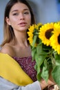 Young happy beautiful girl is walking in dress with a bouquet of sunflowers on a city street. Autumn concept Royalty Free Stock Photo