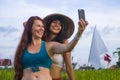 Young happy and beautiful hispanic girl in traditional Asian farmer hat and Caucasian woman taking girlfriends selfie together Royalty Free Stock Photo