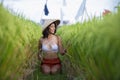 Young happy and beautiful hispanic woman in traditional Asian farmer hat smiling cheerful posing sexy isolated on green rice field Royalty Free Stock Photo