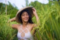 Young happy and beautiful latin woman playing with traditional Asian farmer hat smiling having fun posing sexy isolated on green Royalty Free Stock Photo