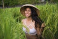 Young happy and beautiful latin woman playing with traditional Asian farmer hat smiling having fun posing sexy isolated on green Royalty Free Stock Photo