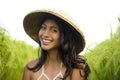 Young happy and beautiful latin woman playing with traditional Asian farmer hat smiling having fun posing sexy isolated on green Royalty Free Stock Photo