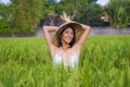 Young happy and beautiful latin woman playing with traditional Asian farmer hat smiling having fun posing sexy isolated on green Royalty Free Stock Photo