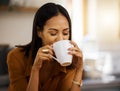 Young happy beautiful mixed race woman enjoying a cup of coffee alone at home. Hispanic female in her 20s drinking a cup Royalty Free Stock Photo