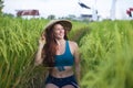 Young happy and beautiful red hair woman in traditional Asian farmer hat smiling cheerful isolated on green rice field in Asia Royalty Free Stock Photo