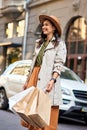 Young happy beautiful and stylish caucasian woman shopping bags wearing autumn grey coat and hat looking aside and Royalty Free Stock Photo