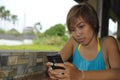 Young happy beautiful and sweet Asian woman sitting in coffee shop using internet app on mobile phone smiling relaxed outdoors Royalty Free Stock Photo