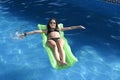 Young happy beautiful woman in bikini and sunglasses lying relax on float airbed at vacation hotel resort swimming pool Royalty Free Stock Photo