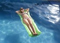 Young happy beautiful woman in bikini and sunglasses lying relax on float airbed at vacation hotel resort swimming pool Royalty Free Stock Photo