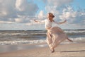 Young happy beautiful woman jumping on a beach in summer. Image of a woman jumping above the ocean at sunset, silhouette