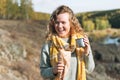 Young happy beautiful woman traveller with curly hair eating hot dog and drinking tea on view background of mountains and river, Royalty Free Stock Photo