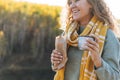 Young happy beautiful woman traveller with curly hair eating hot dog and drinking tea on view background of mountains and river, Royalty Free Stock Photo