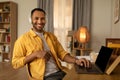 Young happy black man in headphones using laptop pc with mockup, working online at home, copy space Royalty Free Stock Photo