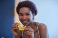 Young happy black woman sits in a bed and eating orange slice. Royalty Free Stock Photo